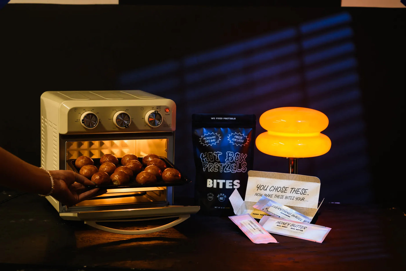 Hand pulling a tray of golden baked pretzel bites out of a warm oven during the late night shoot